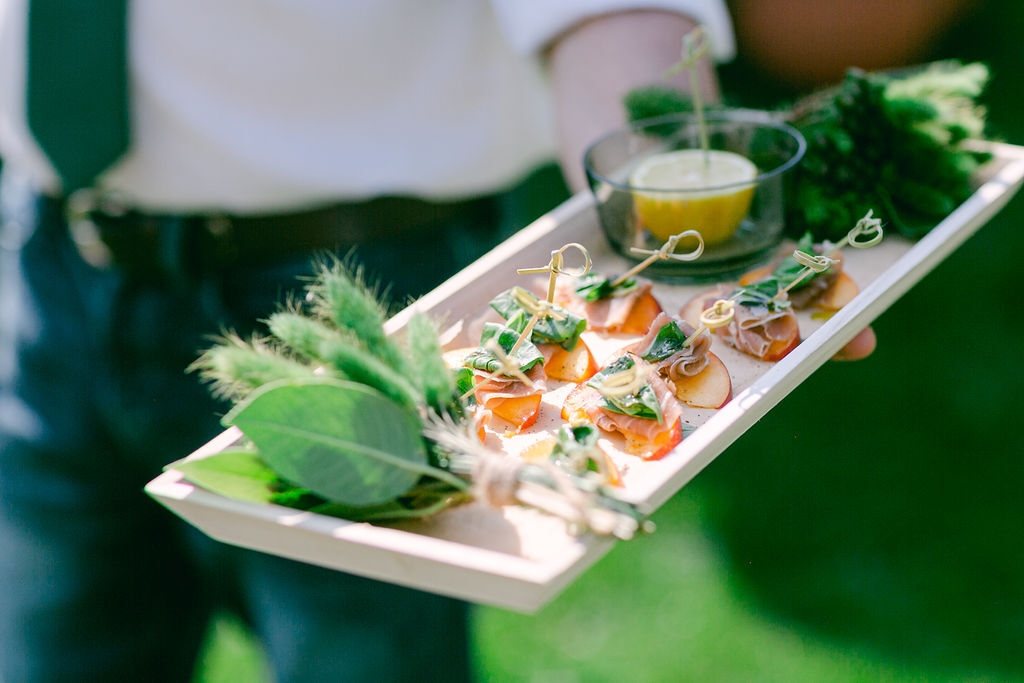 A tray of appetizers featuring fruit and meat