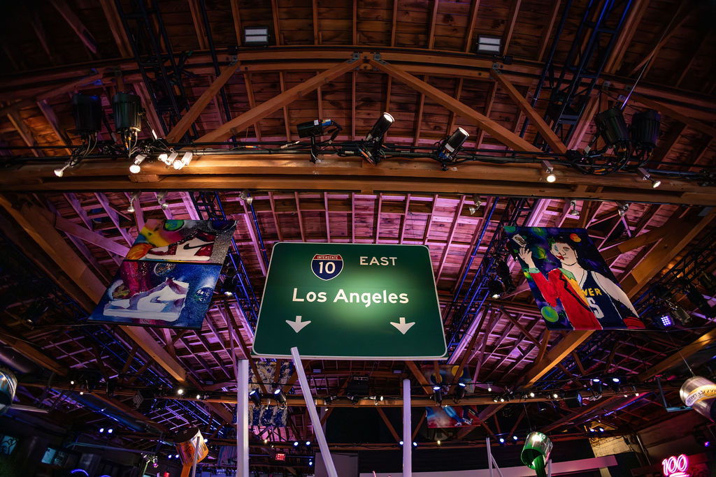 An indoor party with a mock Los Angeles freeway sign attached to the ceiling